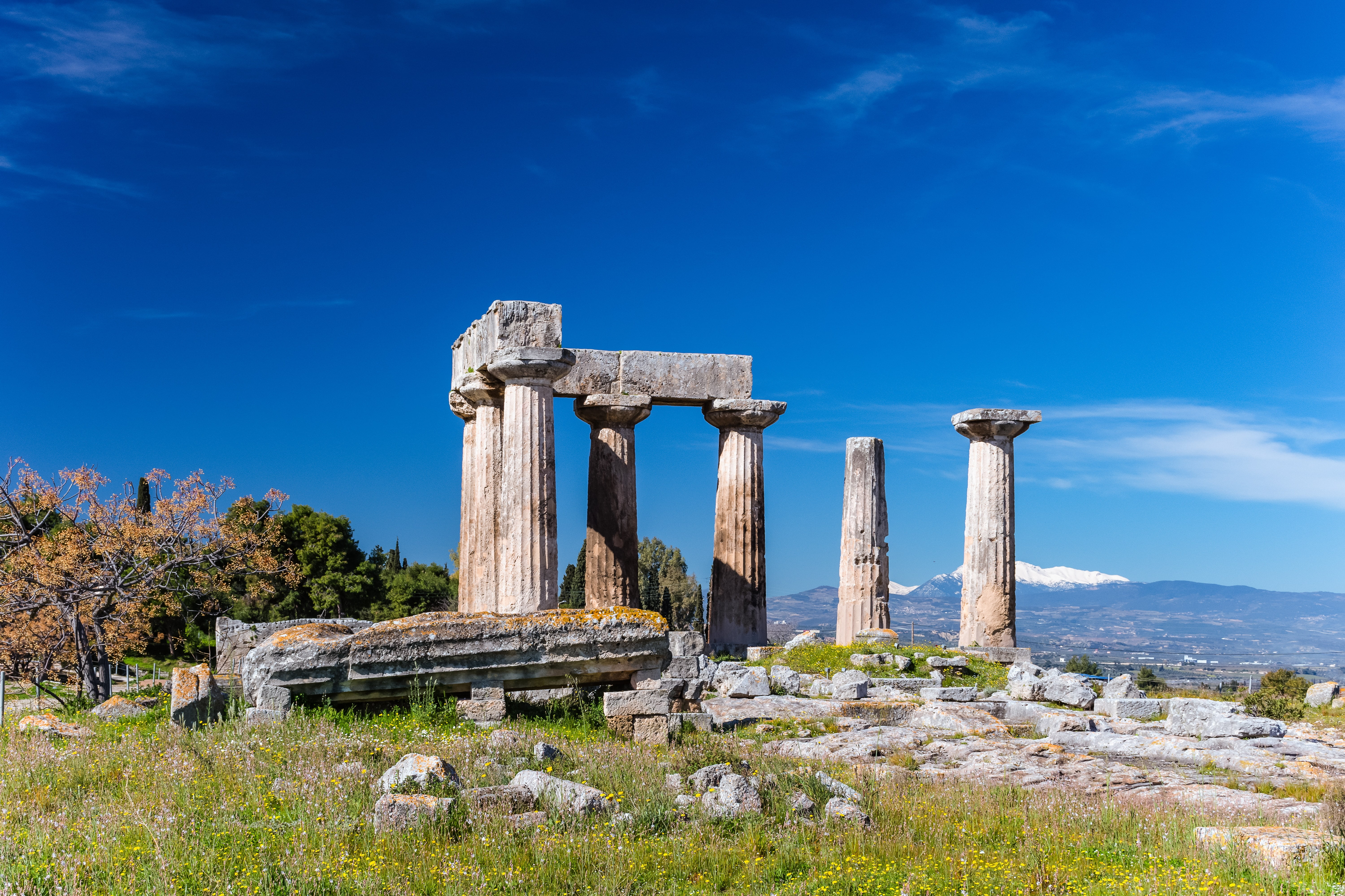Ruins of Doric Temple of Apollo (6th c. B.C.) in Ancient Corinth, Greece with blue sky background. Ancient Corinth in Greece.